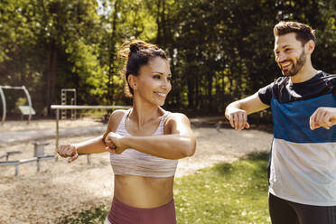 Mann und Frau dehnen sich in der Nähe eines Fitnessparcours - MFF04852