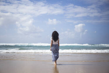 Rückenansicht einer Frau, die am Strand steht und auf das Meer schaut, Fuerteventura, Spanien - ABZF02514