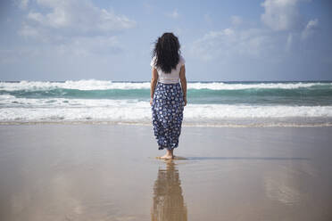 Rückenansicht einer Frau, die am Strand steht und auf das Meer schaut, Fuerteventura, Spanien - ABZF02515