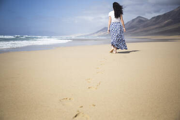 Rückenansicht einer Frau, die am Strand spazieren geht, Fuerteventura, Spanien - ABZF02518