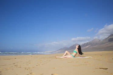 Frau beim Sonnenbad am Strand, Fuerteventura, Spanien - ABZF02527