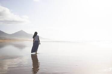 Rückenansicht einer Frau, die am Strand spazieren geht, Fuerteventura, Spanien - ABZF02530