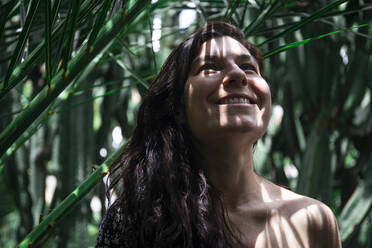 Portrait of smiling woman at palm tree, Fuerteventura, Spain - ABZF02534