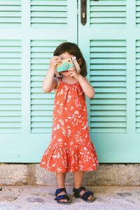Kleines Mädchen spielt mit Holzspielzeug Kamera trägt roten Kleid mit Blumenmuster - GEMF03115