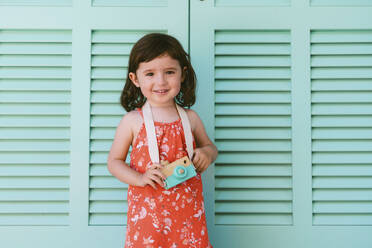 Porträt eines lächelnden kleinen Mädchens mit Holzspielzeugkamera - GEMF03117