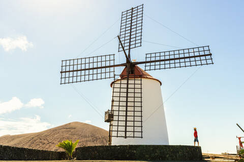 Mann neben einer alten Windmühle, Lanzarote, Kanarische Inseln, Spanien, lizenzfreies Stockfoto