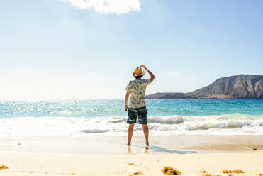 Rückansicht eines Mannes mit Hut am Playa de las Conchas, Lanzarote, Kanarische Inseln, Spanien - KIJF02640