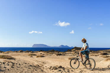 Mann auf einem Fahrrad, Insel La Graciosa, Lanzarote, Kanarische Inseln, Spanien - KIJF02641