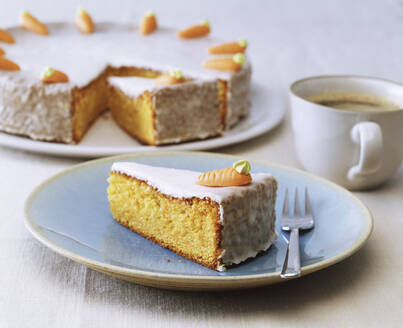 Close-up of carrot cake slice in plate with coffee cup on table - PPXF00264