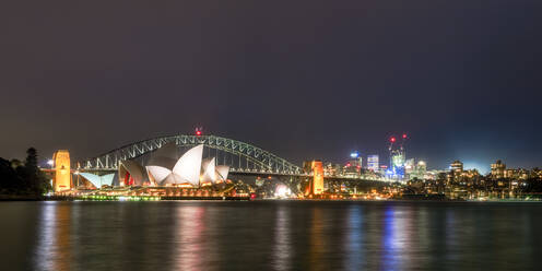 Illuminated Sydney Harbor Bridge and buildings over river against sky at night, Australia - SMA01327