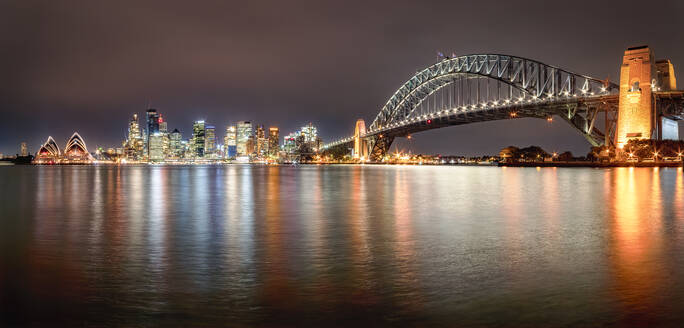 Panoramaaufnahme der beleuchteten Sydney Harbor Bridge über dem Fluss gegen den Himmel bei Nacht, Sydney, Australien - SMAF01330