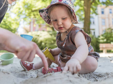 Porträt eines kleinen Mädchens mit seiner Mutter im Sandkasten auf dem Spielplatz - LAF02353