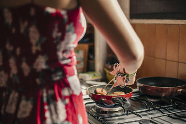 Nahaufnahme einer Frau beim Kochen in der Küche mit einer Pfanne - ACPF00585