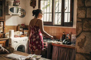 Rear view of woman cooking in kitchen - ACPF00588