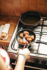 Close-up of a woman cooking croquettes in a pan - ACPF00590