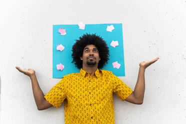 Young man wearing yellow shirt, blue indicating label with arrow signs - AFVF03839