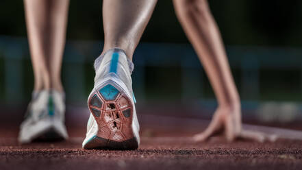 Legs of female athlete running on tartan track - STSF02193