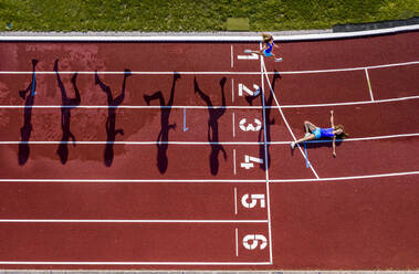 Aerial view of a running and lying young female athlete on a tartan track - STSF02196