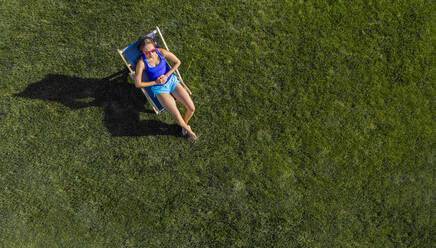 Luftaufnahme einer jungen Frau beim Sonnenbaden auf einer Wiese - STSF02199