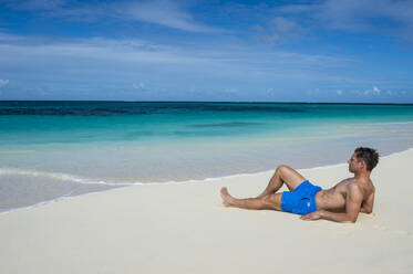 Ein Mann entspannt sich am Weltklasse-Strand von Shoal Bay East, Anguilla, Britisches Überseegebiet, Westindien, Karibik, Mittelamerika - RHPLF03740
