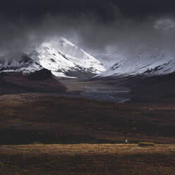 Hiker illuminated by a beam of sunlight after snowfall in the Denali National Park, Alaska, United States of America, North America - RHPLF03804