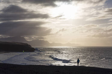 Einsamer Mann mit Blick auf die dramatische Küstenlinie von Playa del Viejo Rey bei La Pared auf der Vulkaninsel Fuerteventura, Kanarische Inseln, Spanien, Atlantik, Europa - RHPLF03917