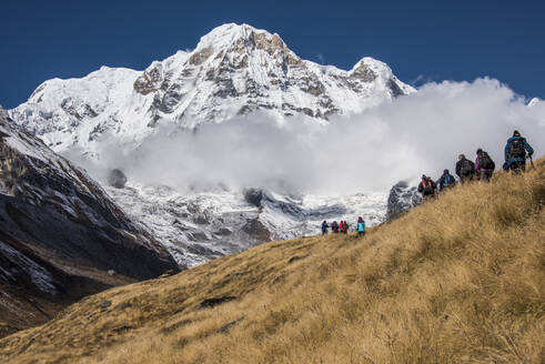 Eine Gruppe von Wanderern, die sich dem Annapurna Base Camp nähert, mit dem Annapurna South im Hintergrund, Himalaya, Nepal, Asien - RHPLF04072