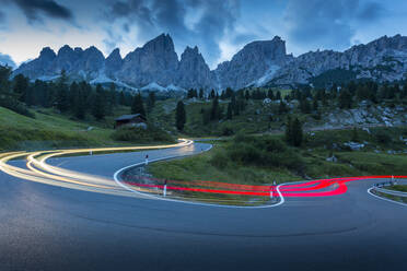 Autowegbeleuchtung am Pordoipass mit Bergkulisse in der Abenddämmerung, Provinz Bozen, Südtirol, Italienische Dolomiten, Italien, Europa - RHPLF04109