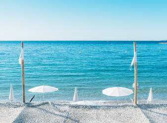 Riesiger weißer Sonnenschirm neben dem Meer vor blauem Himmel in Juan les Pins, Cote d'Azur, Provence, Frankreich, Mittelmeer, Europa - RHPLF04149