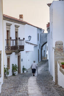Eine alte Frau geht durch eine Gasse im Bergdorf Marvao im Alentejo, Portugal, Europa - RHPLF04438