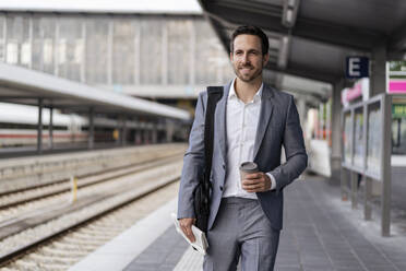 Geschäftsmann mit Kaffee zum Mitnehmen auf dem Bahnsteig - DIGF08108