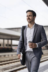 Geschäftsmann mit Kaffee zum Mitnehmen auf dem Bahnsteig - DIGF08109