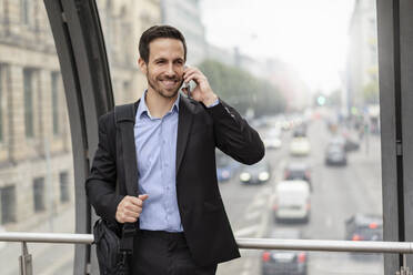 Smiling businessman on cell phone in the city - DIGF08116