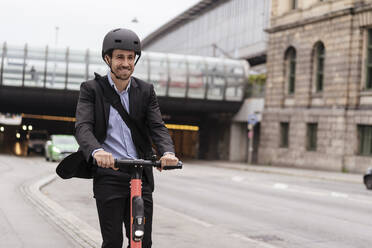 Businessman riding e-scooter in the city - DIGF08122