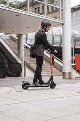 Businessman riding e-scooter in the city - DIGF08125