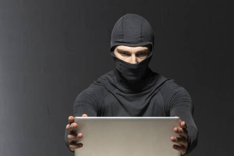 Maskierter Hacker mit Laptop, lizenzfreies Stockfoto