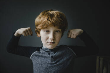 Portrait of redheaded boy flexing muscles - KNSF06245
