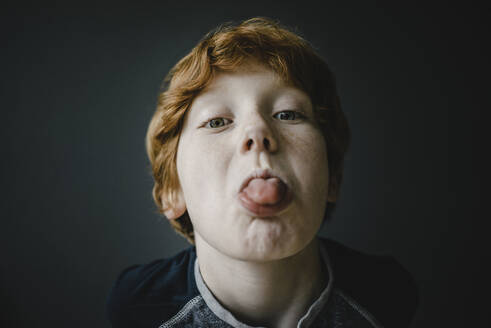 Portrait of redheaded boy sticking out tongue - KNSF06247