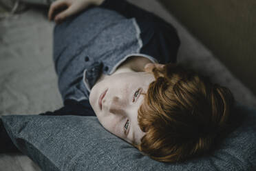 Porträt eines träumenden Jungen, der auf der Couch liegt und in die Ferne schaut - KNSF06258