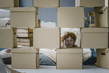 Porträt eines lächelnden Jungen mit Pappkartons im neuen Zuhause - KNSF06274