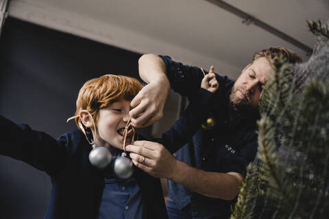 Father decorating his son at Christmas time stock photo