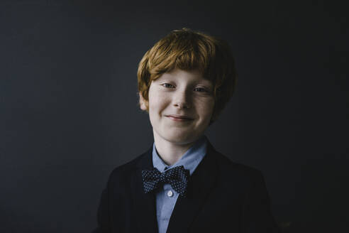 Portrait of smiling redheaded boy wearing bow tie - KNSF06278