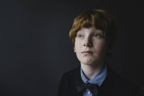 Portrait of redheaded boy with freckles wearing bow tie looking up - KNSF06279