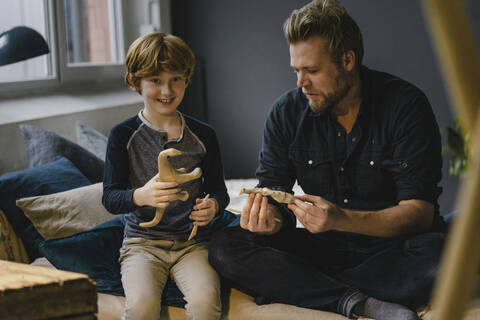 Portrait boy sitting with his father on couch kneading dinosaur stock photo