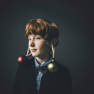 Portrait of redheaded boy wearing bow tie and Christmas baubles - KNSF06302