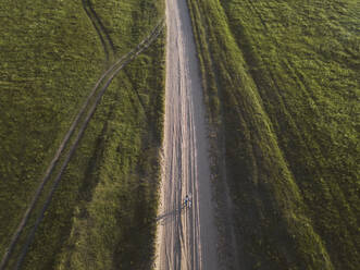 Luftaufnahme einer Frau mit Fahrrad auf einem unbefestigten Weg inmitten der Landschaft, Tichwin, Russland - KNTF03037