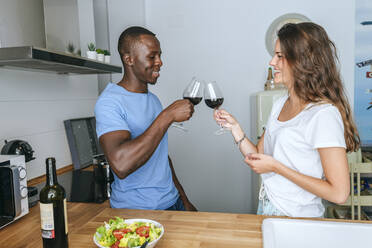 Ehepaar stößt in der Küche mit Wein an - KIJF02650