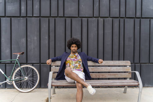 Stilvoller Mann mit Fahrrad auf einer Bank sitzend - AFVF03848