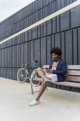 Stylish man using cell phone on a bench - AFVF03852