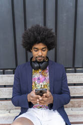 Stilvoller Mann benutzt Handy auf einer Bank - AFVF03853